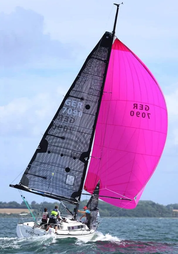 X-332 SOPHUS sailing with a reefed black X-Drive® mainsail and full magenta spinnaker, GER 7090, three crew aboard