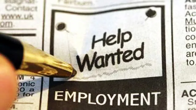 Pen pointing at a Help Wanted advert in a newspaper employment section