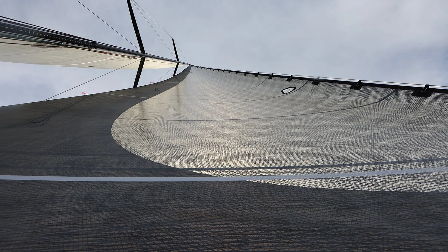 Looking up a dark grey laminate genoa from the deck, an open-weave section contrasting with the taffeta-covered panels