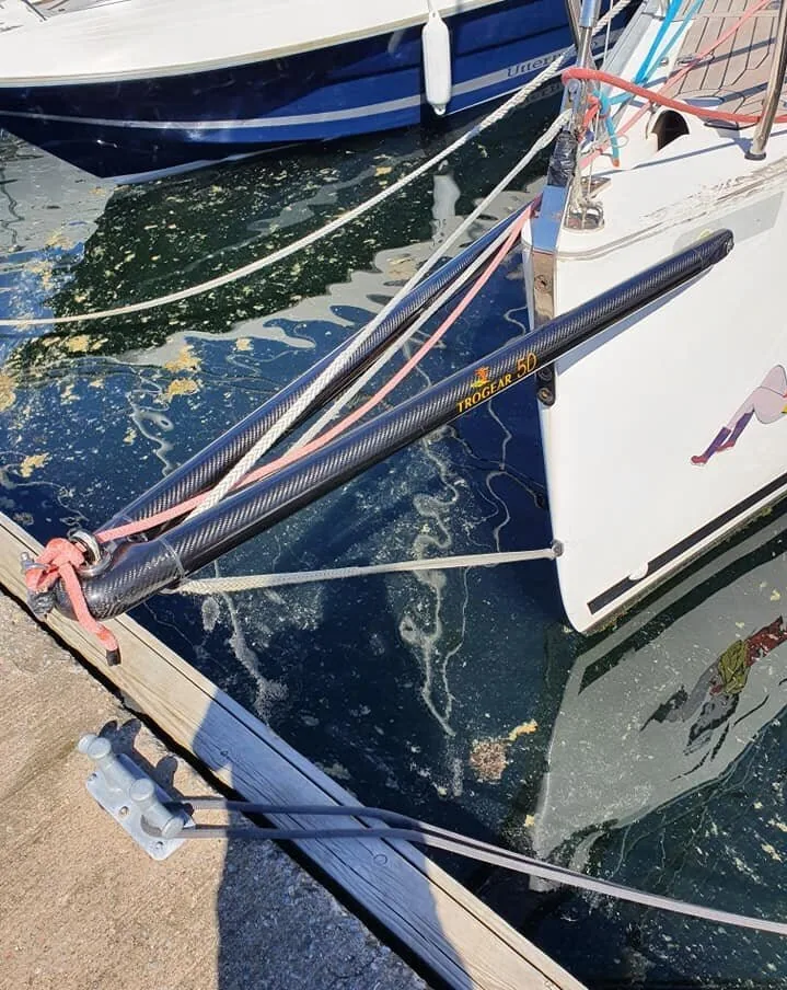Close-up of a carbon-fibre bowsprit with its bobstay fitted to a keelboat's bow at the dock